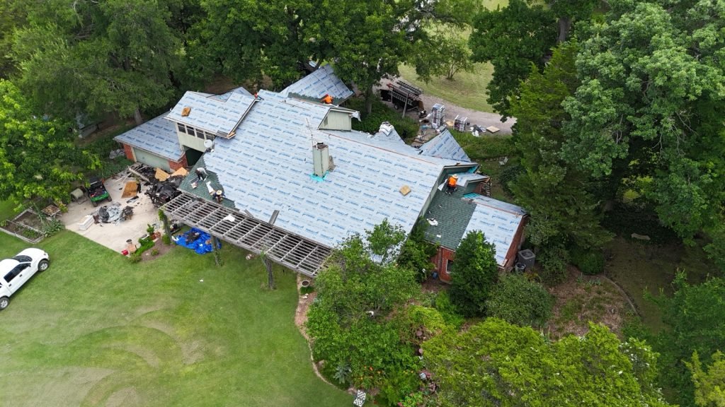 Roofing crew installing synthetic underlayment across a large residential roof