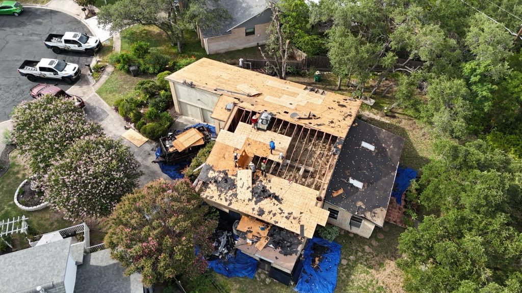 Storm-damaged roof tear-off with tarps and crew on site